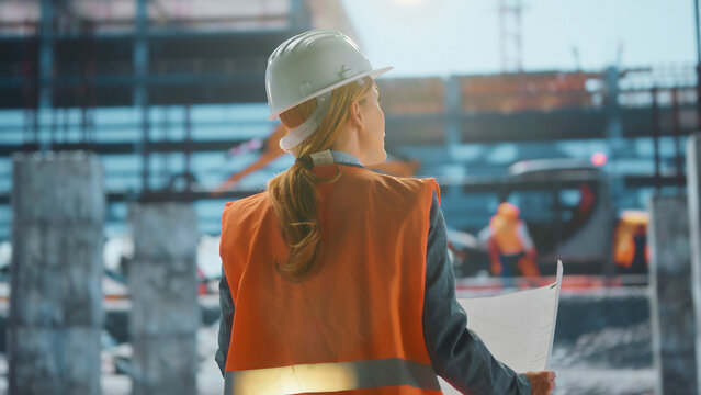 Female engineer holding blueprint supervising construction site progress