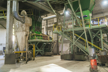 Inside a wood processing factory, a large industrial wood chipper transforms timber into sawdust,...