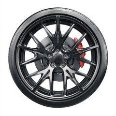Fototapeta premium A close-up shot of a sleek, modern car wheel. The wheel boasts a sophisticated design with a shiny black rim, a red brake caliper, and a high-performance tire.