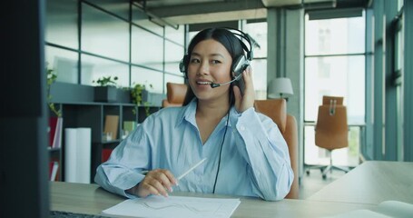 A young professional wearing a headset is actively engaged and participating in a video call in a bright office space - Powered by Adobe