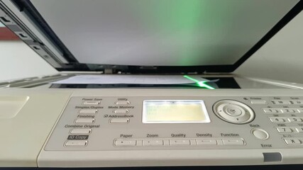 Footage of a multifunction photocopier in operation, equipped with a control panel.