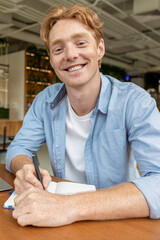 Smiling young man in blue shirt looking contented and happy