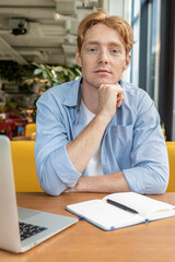 Ginger young man sitting at the table in the cafe