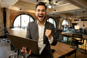 Caucasian young man in the office looking excited and happy