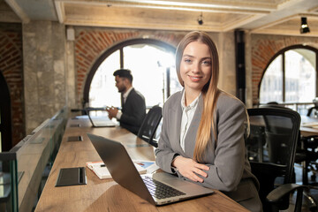 Pretty young woman sitting in the office at the laptop