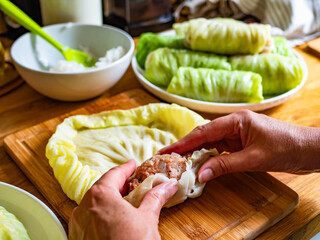 Cooking stuffed cabbages on wooden table - polish cuisine golabki