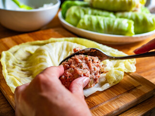 Cooking stuffed cabbages on wooden table - polish cuisine golabki