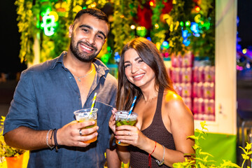 Happy couple enjoying cocktails at night market