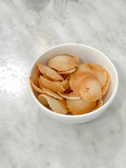 Crispy golden keropok served in a white bowl on marble, a traditional Malaysian snack with irresistible crunch and aroma.