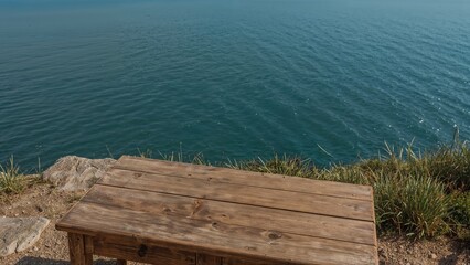 Fototapeta premium Rustic wooden table overlooking serene ocean view on a cliffside