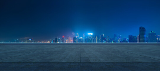 Empty tiled plaza overlooks a modern night city skyline