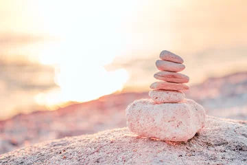 Selbstklebende Fototapeten Zen Steine Stacked stones balanced on a beach at sunset, symbolizing peace and harmony in nature.  © Bits and Splits