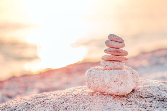 Stacked stones balanced on a beach at sunset, symbolizing peace and harmony in nature.