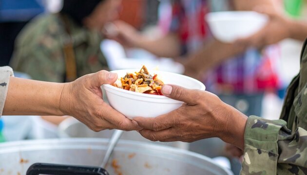 Hands offer a hot meal during a community event, promoting acts of kindness. Food is served with warmth and care