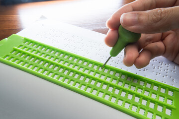 Writing Braille with Braille Slate and Stylus. Text on the paper is a dummy Lorem ipsum text.