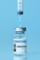 Bottle of Lenacapavir vaccine with syringe on blue background and copy space, illustrating HIV prevention and treatment through modern medicine, healthcare technology, and pharmaceutical innovation