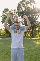 A family, a father and daughter on their shoulders in the park, happiness or love in the summer sun.