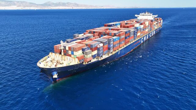 Aerial drone video over colorful truck size container ship cruising in open ocean deep blue Mediterranean sea