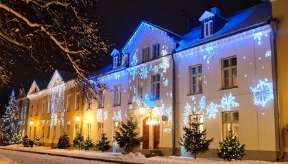 Festive historic building illuminated with blue snowflake light projections during a snowy winter night for the Christmas holiday season