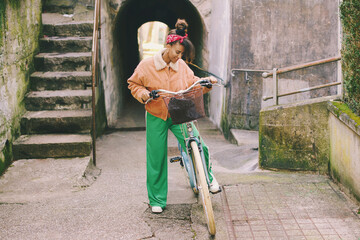 Outdoor fashion portrait of pretty african woman walking with bicycle