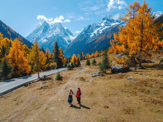 Aerial view of Couple tourist relaxing at Mount Siguniang national park with the Beautiful snow mountains in autumn, Chengdu ,Sichuan in China.