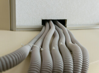 Upward view of wires in corrugated plastic protective sleeves running along the wall under a...