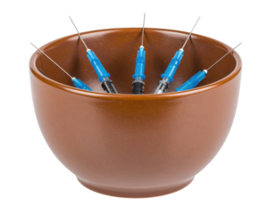 A brown bowl contains six blue and black syringes with needles pointing upwards.