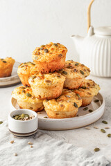 Savory zucchini muffins with cheese and seeds on a plate on white kitchen table background. Healthy and quick morning breakfast