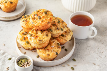 Savory zucchini muffins with cheese and seeds on a plate on white kitchen table background. Healthy and quick morning breakfast