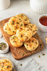 Savory zucchini muffins with cheese and seeds on wooden board on white kitchen table background. Healthy and quick morning breakfast