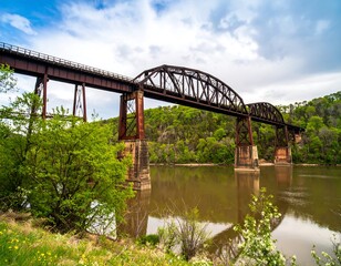 Rusty railroad bridge over a river. Lush greenery