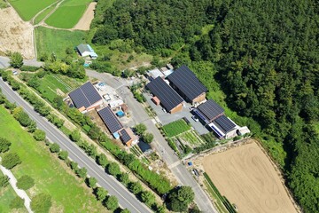 Aerial View of Rooftop Solar Panel Installation on Rural Business and Residential Buildings –...