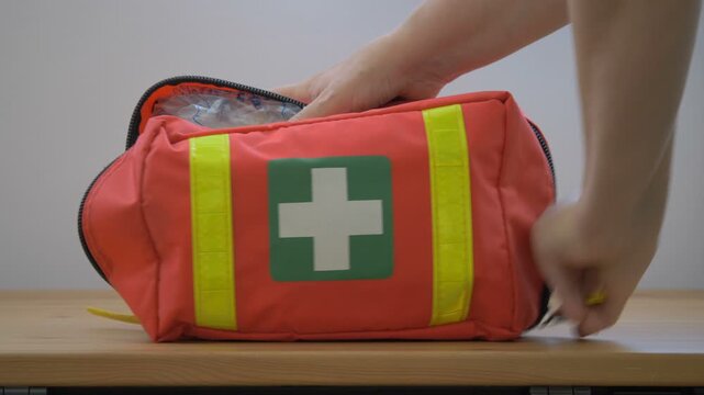 Hands are grabbing bandage from the first aid kit