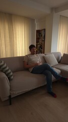Obraz premium Young Man Relaxing at Home on a Cozy Sofa