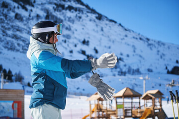 Woman putting on gloves at snowy mountain ski resort