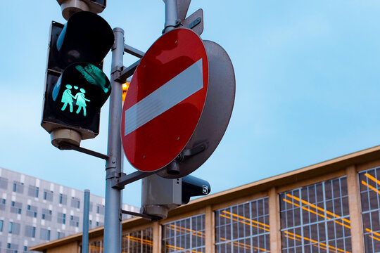Traffic light with same-sex couple pedestrian symbol and no-entry sign against modern buildings at dusk outside Wein Westbahnhof in central Vienna. - Powered by Adobe