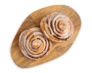 Top view of two delicious homemade cinnamon rolls bun served on brown wooden cutting board isolated on white background used as sweet baked pastry dessert for breakfast or comfort food for brunch