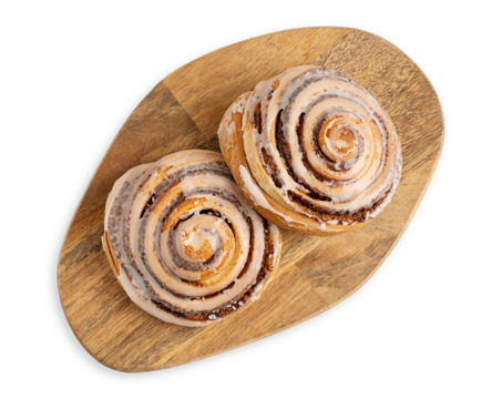 Top view of two delicious homemade cinnamon rolls bun served on brown wooden cutting board isolated on white background used as sweet baked pastry dessert for breakfast or comfort food for brunch