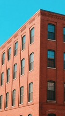 Red Brick Building with Symmetrical Windows Against a Clear Blue Sky