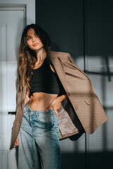 A woman in jeans and a blazer basks in the glow of natural light, embodying a blend of sophistication and casual elegance in a modern setting.