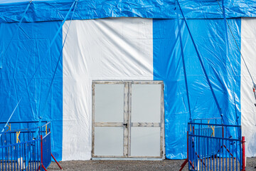 Bright blue circus tent raised in a bustling outdoor location, preparing for exciting performances and attractions in the warm afternoon sun © fottoo