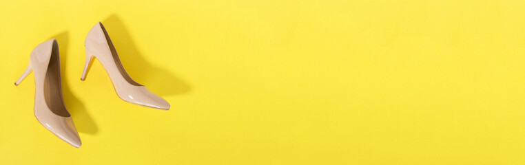 Classic beige women's shoes with medium heels on a yellow background. The concept of sales and advertising. flatly. From above.