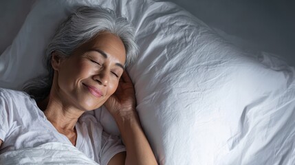 Senior asian woman resting peacefully, lying comfortably in bed with soft smile, demonstrating serene nighttime sleeping experience and wellness