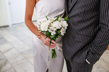 groom embraces the bride with wedding bouquet. rings on the hands of newly-married couple. bride put her hands on the shoulders of the bridegroom.