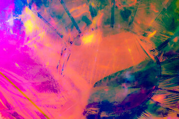 A vibrant, abstract artwork featuring a close-up of a shiny, surface reflecting multicolored light. The dominant hues are red, orange, yellow, and pink, with hints of blue and green.