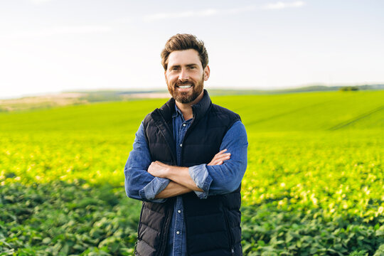 Portrait of smiling farmer standing in cultivated field with arms crossed