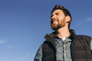 Farmer smiling and looking up at clear sky, hopeful for good weather