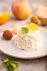 White Сottage cheese, Curd, with orange and lychee on brown concrete and orange textile, side view, close up, selective focus