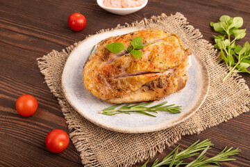 Fried Turkey Thigh with spices on plate on brown wooden, linen textile. side view, close up