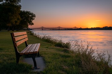 Serene riverside sunset with empty bench and bridge in the distance
